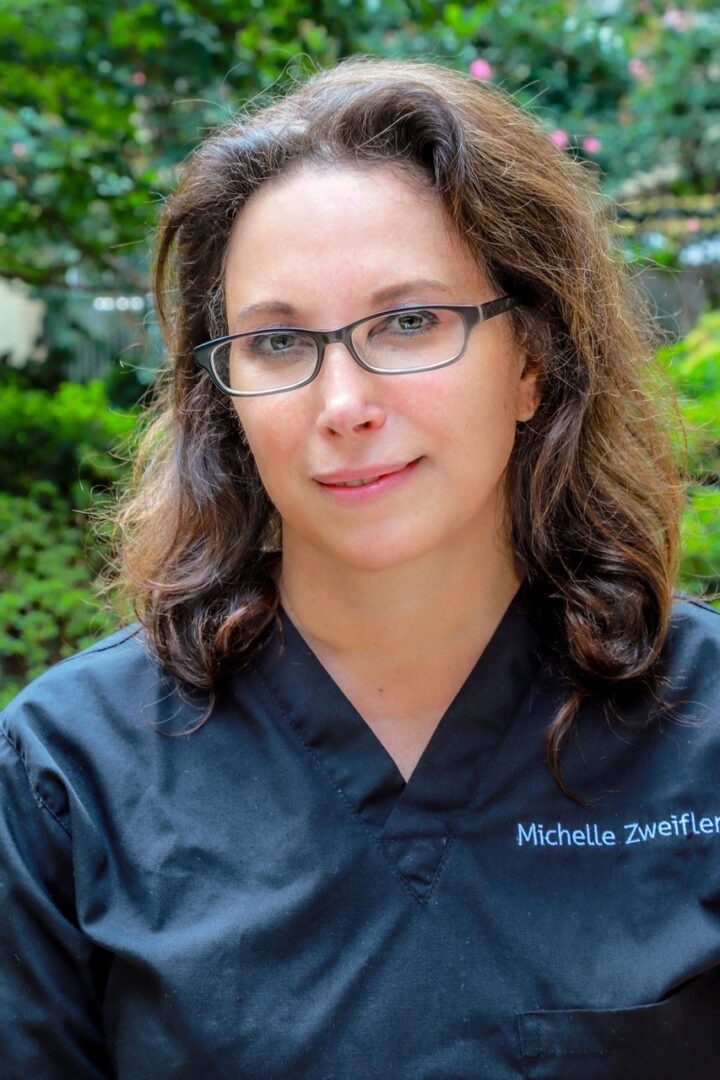 A woman in a black scrub shirt is posing for a photo.