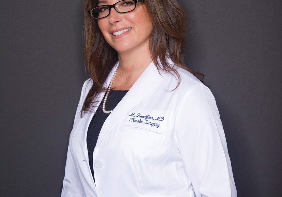 A woman in a white lab coat posing for a photo.